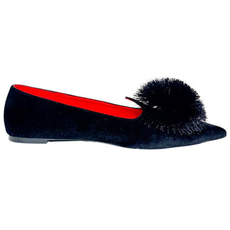 A single black velvet flat shoe with a large black pom-pom detail on the toe and a bright red interior lining, shown against a plain white background.