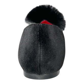 A single black velvet shoe with a fluffy black faux fur pom-pom trim on the toe, shown from the back against a white background.